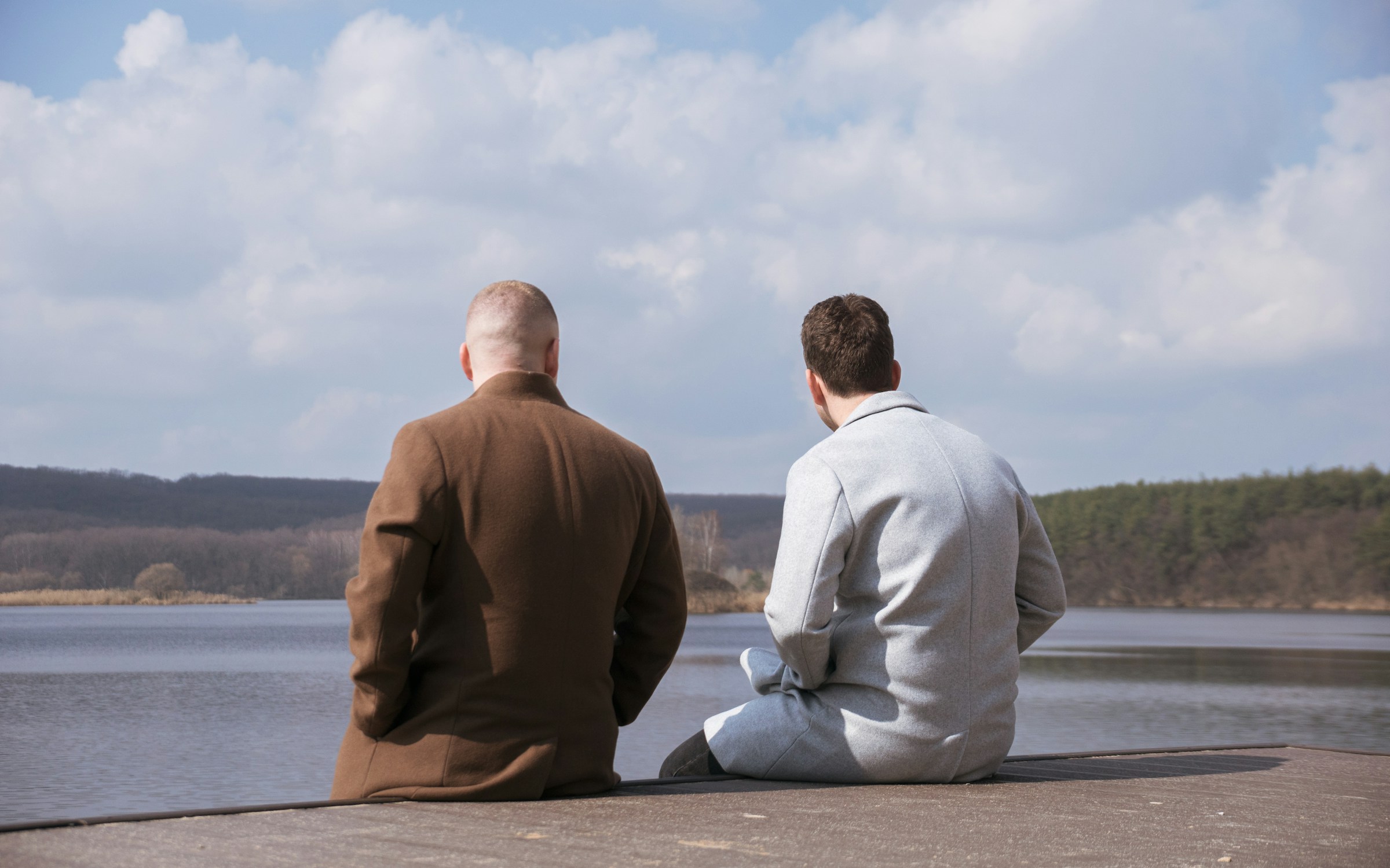 Two people sitting on river bank talking to each other