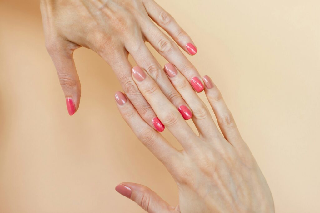 Woman’s hands with a soft pink American manicure, featuring a clean and natural nail look.