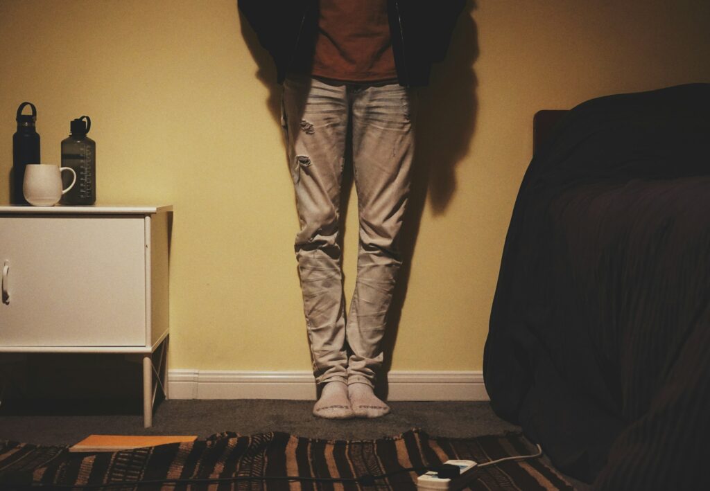 A person wearing tan corduroy pants standing in front of a wall, showcasing a modern and stylish street-style outfit.