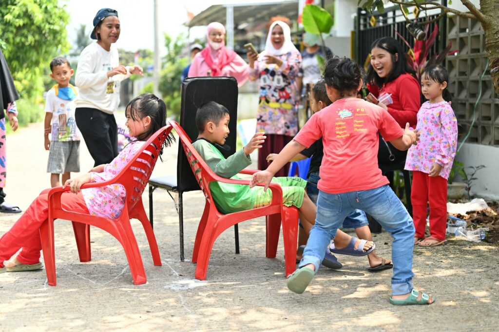 2 kids sitting on chairs and others standing beside them
