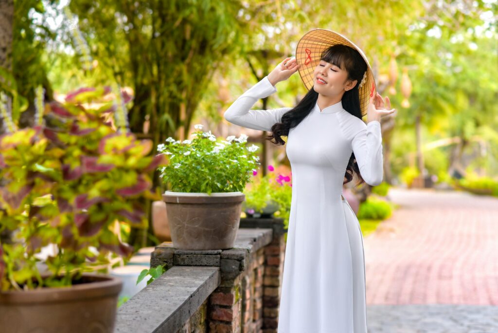 A women in white tea party fashion dress standing beside a brick wall