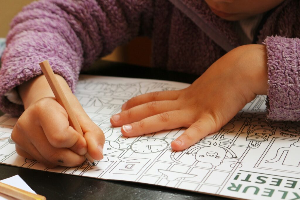 A kid doing shape hunt on a notebook with a pencil in hand