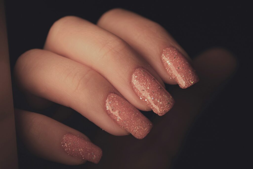 Close-up of a woman's hand with soft pink French nails.