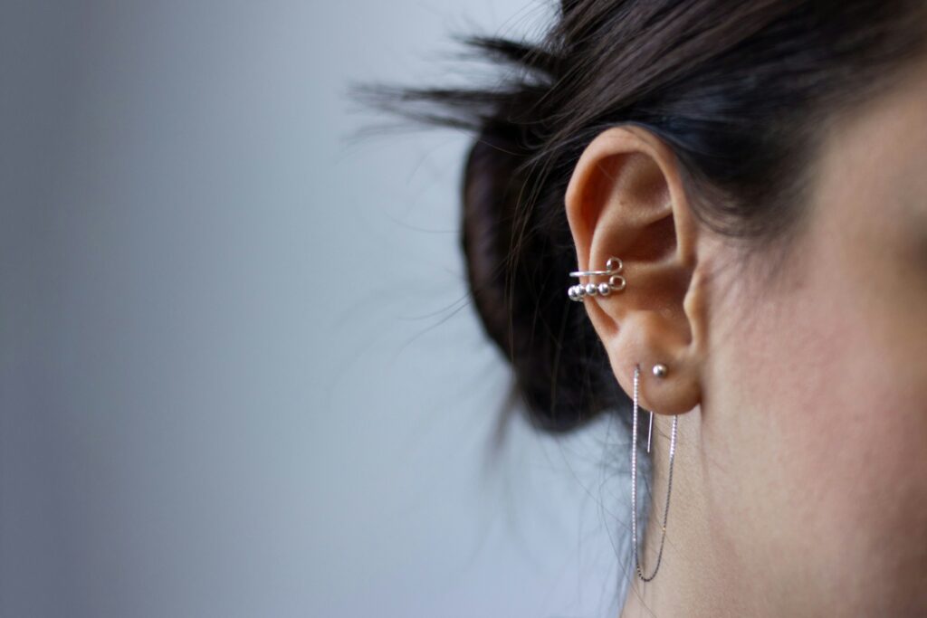 Close-up of multiple ear cartilage piercings with silver jewelry, highlighting stylish ear placement similar to a rook piercing.