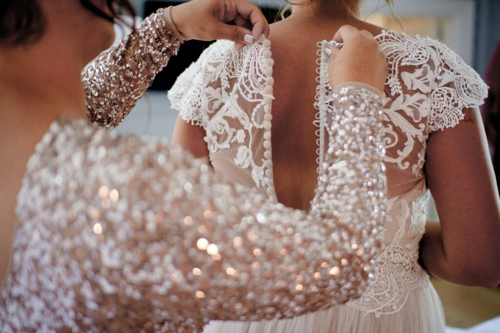A woman zipping up a bride's dress.