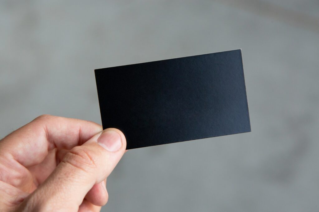 Close-up of a person holding minimalist black business cards, showcasing sleek and modern branding design.