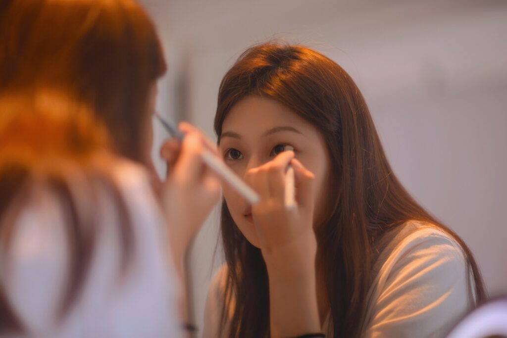 Woman doing eye makeup at a vanity mirror, representing tubing mascara application and beauty routine.