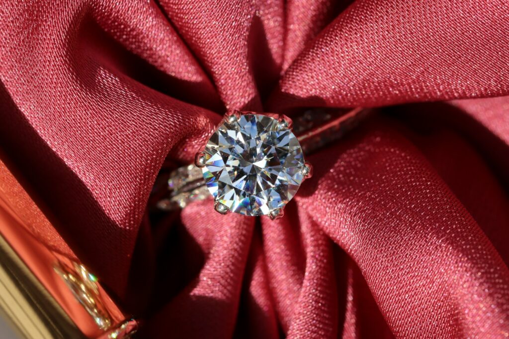 Close-up of a 3 carat diamond ring on a red satin background showcasing brilliance and timeless glamor.