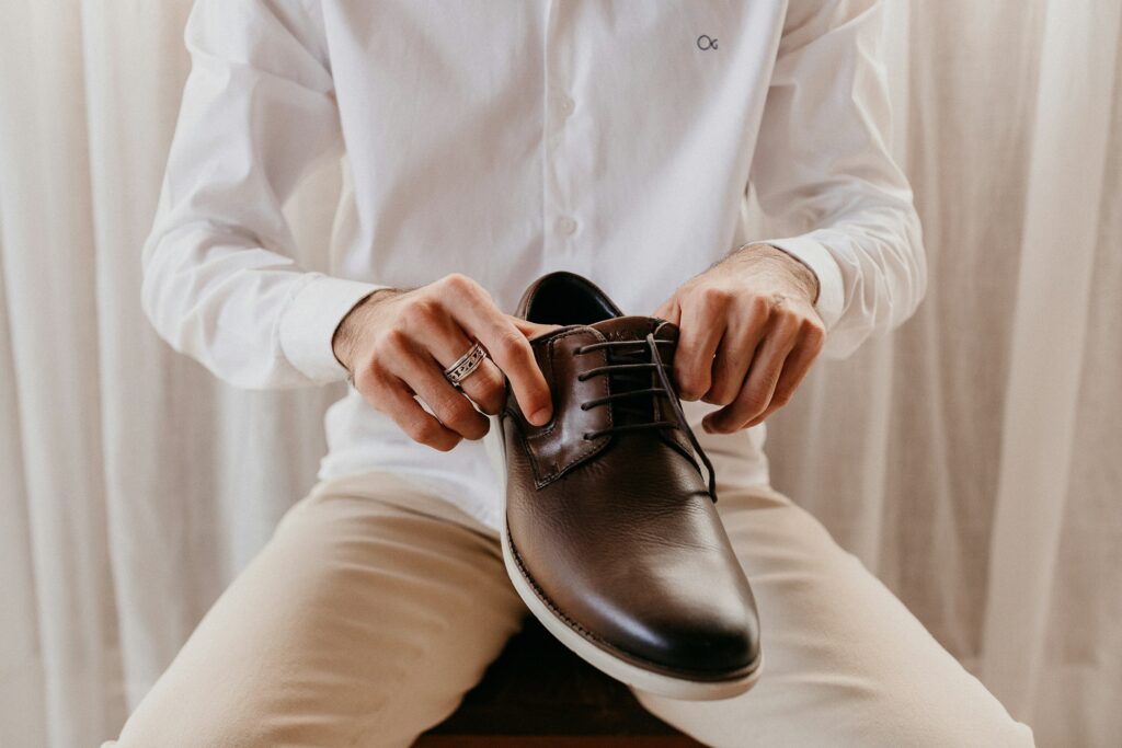 Person holding black leather business casual shoes, showcasing stylish and comfortable footwear for office wear.