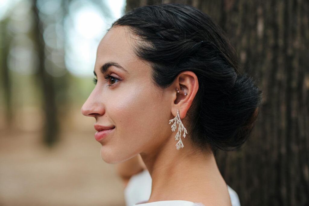 Woman with visible conch piercing in an elegant outdoor setting, showcasing ear jewelry style.