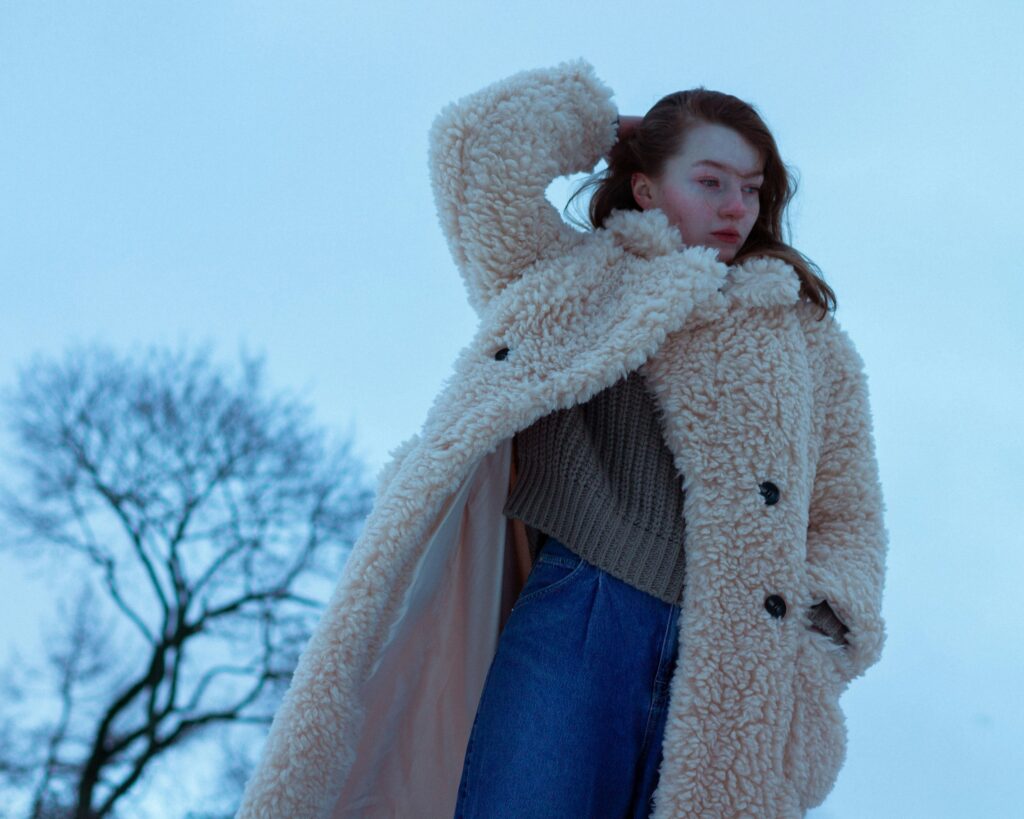 Woman wearing a cozy fur and coat in a winter landscape, showcasing effortless glamor and style.