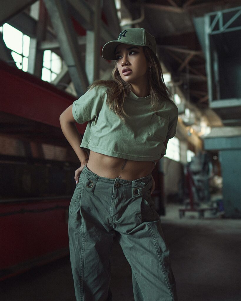 Fashion-forward woman wearing green cargo pants ladies style, paired with a cropped top and cap in an urban setting.