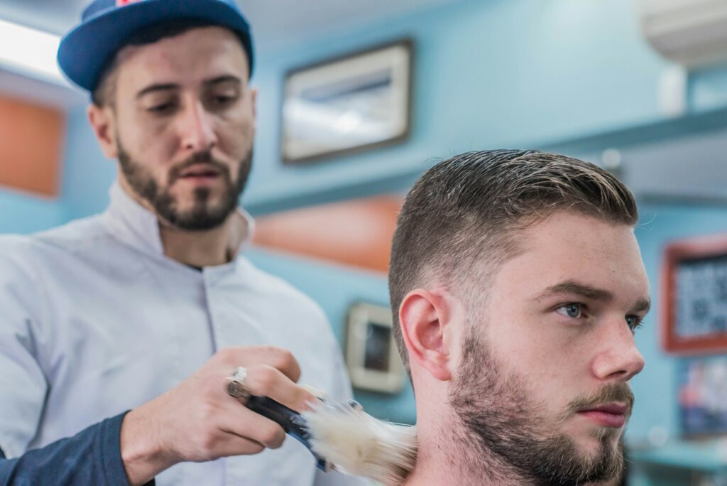 Barber giving a man a clean high and tight haircut with short sides and a neat top in a modern barbershop.