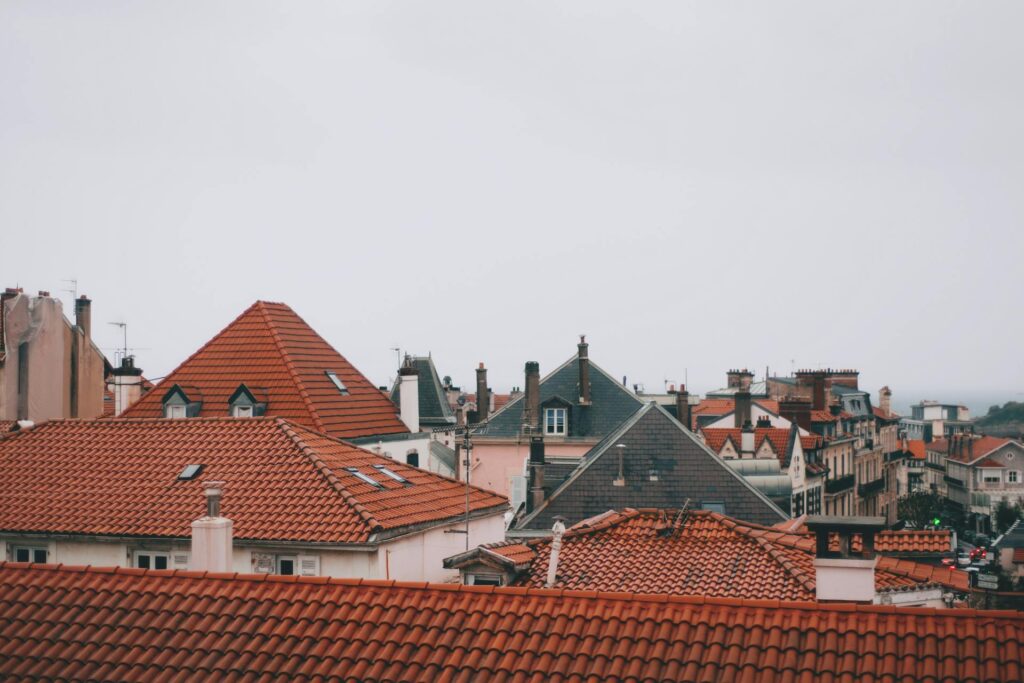 A residential home featuring a classic hip roof under a cloudy sky, showcasing durable and stylish roofing design.