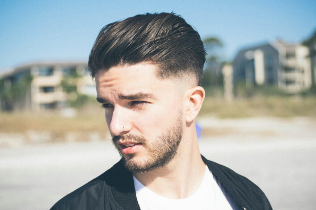 Man with a low fade haircut wearing a black and white dress, showcasing a clean and stylish modern fade.