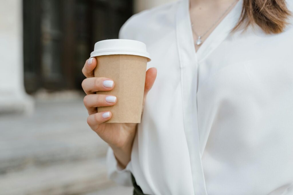 Woman holding a coffee cup with a pappedeckel lid, promoting eco-friendly alternatives to plastic.