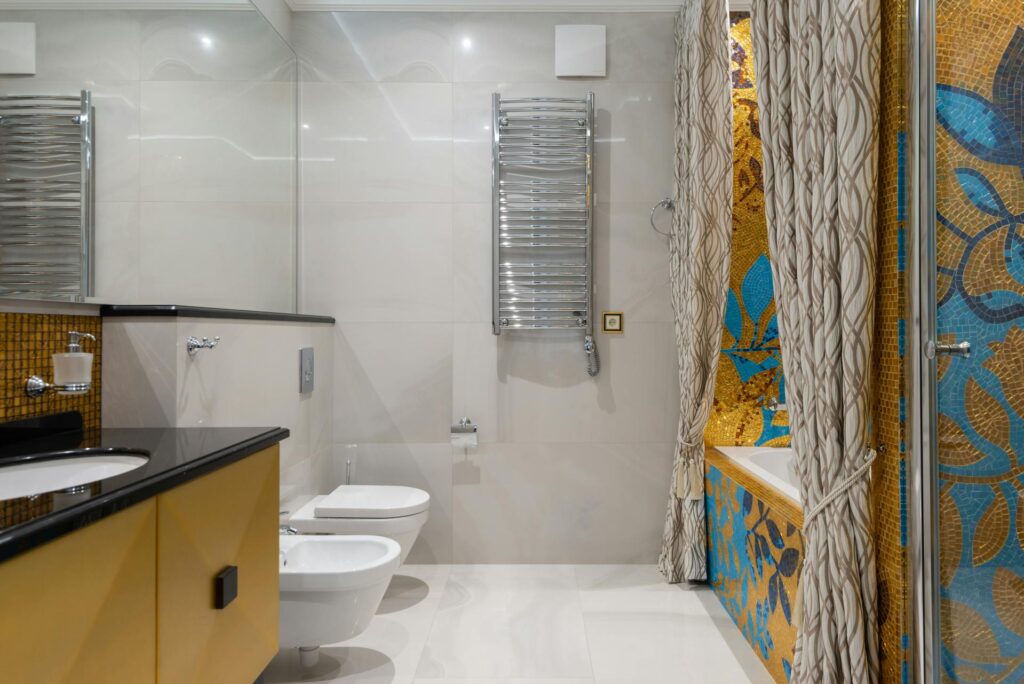 Modern bathroom with yellow mosaic tile walls, featuring a patterned shower curtain and white bathtub.