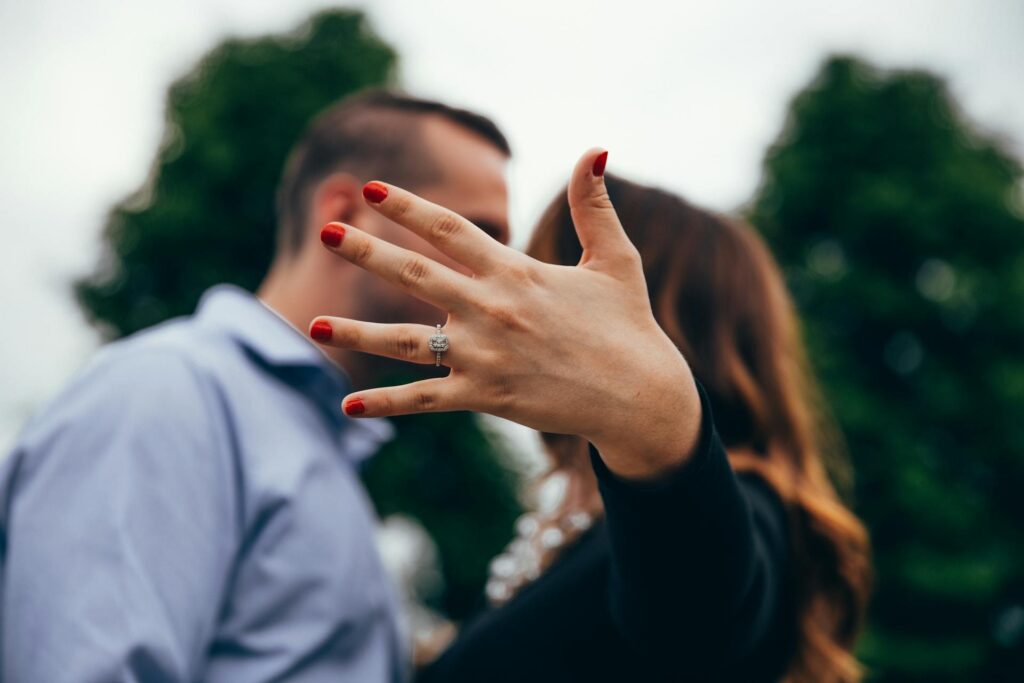 Woman showing her diamond engagement ring with red nails, symbolizing love and commitment.