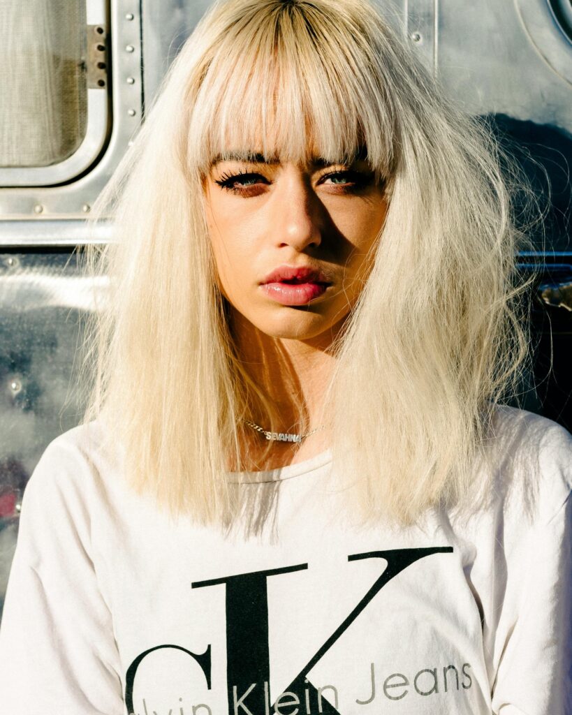 Wolf cut hairstyle with blonde layers and full fringe, showcasing the bold and textured hair trend of 2025.