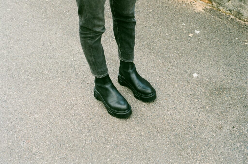 Black square toe Chelsea boots with chunky lug sole styled with slim gray jeans on city pavement for effortless fall 2026 outfit.