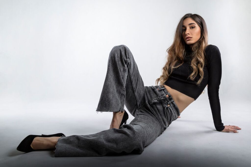 Woman wearing dark wash wide-leg jeans with black crop top and heels.