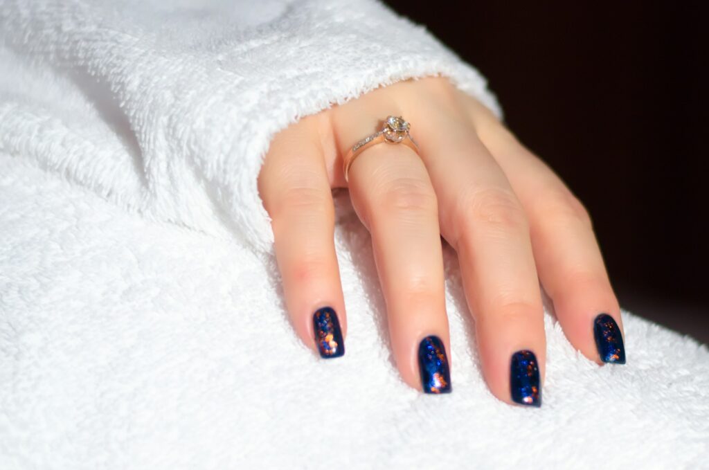 Magnetic nail enamel in deep navy blue with copper gold shimmer effect on square nails.