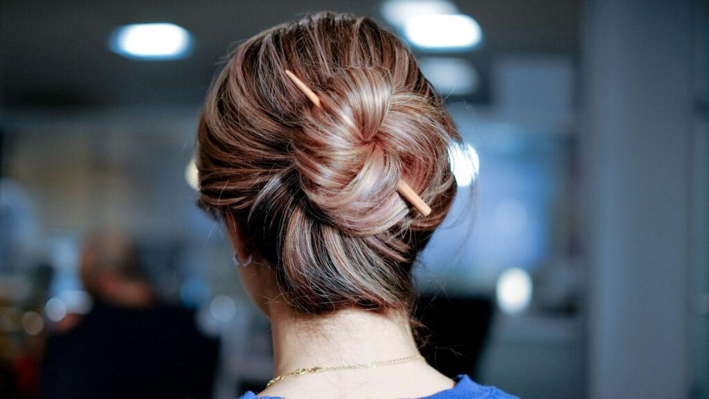 Close-up of a twisted low bun updo secured with a hairpin. 