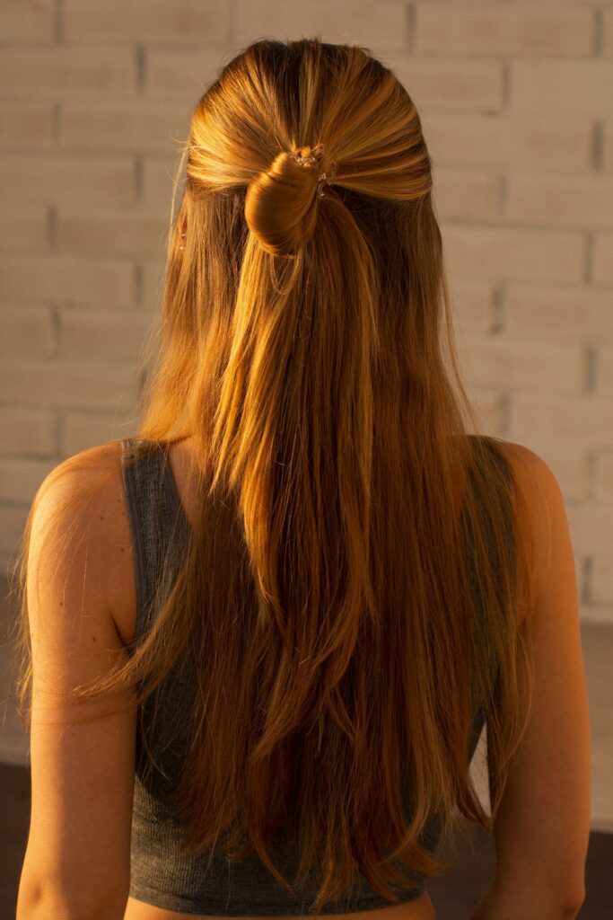Half-up straight hairstyle featuring smooth long hair secured with a twisted hair wrap.