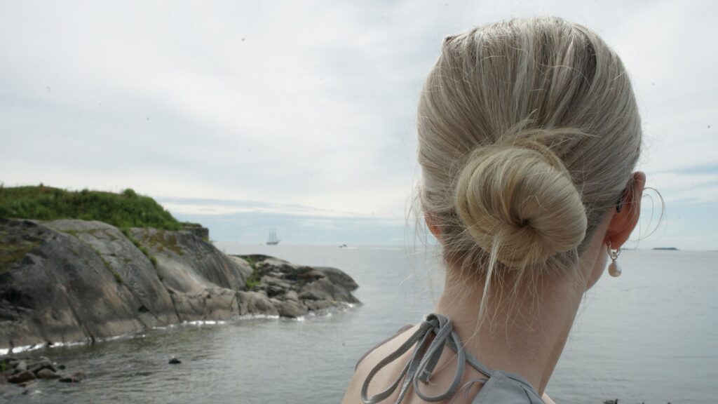Back view of a low twisted bun updo styled on long blonde hair outdoors.
