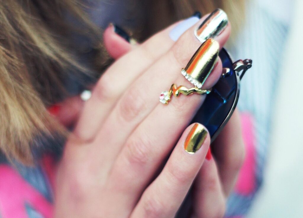 Close-up of gold and silver chrome nails with a mirror-like metallic finish