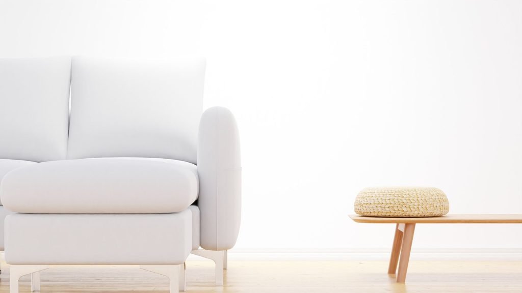 minimalist white couch with woven pouf accent table