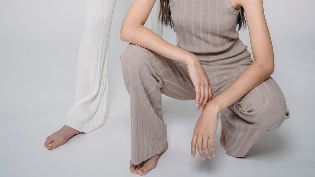 Close-up of two women's legs wearing ribbed knit trousers in taupe and white