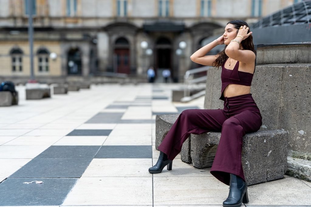 Woman wearing a fitted burgundy crop top tucked into matching wide-leg pants, styled with black heeled ankle boots