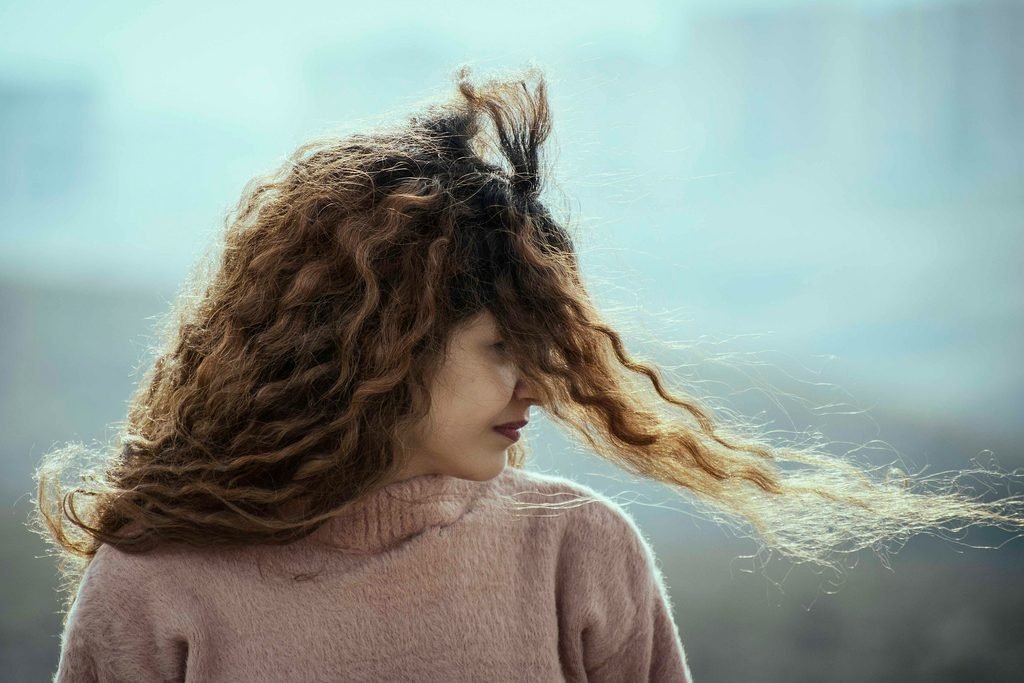 Woman with frizzy curly hair blowing in the wind outdoors